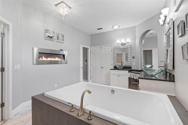 bathroom featuring a bathtub, vanity, and a notable chandelier