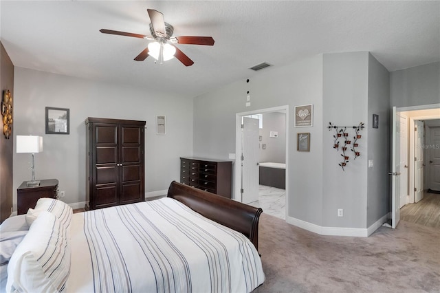 bedroom featuring a textured ceiling, ensuite bath, light carpet, and ceiling fan