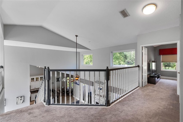 corridor with lofted ceiling and carpet flooring