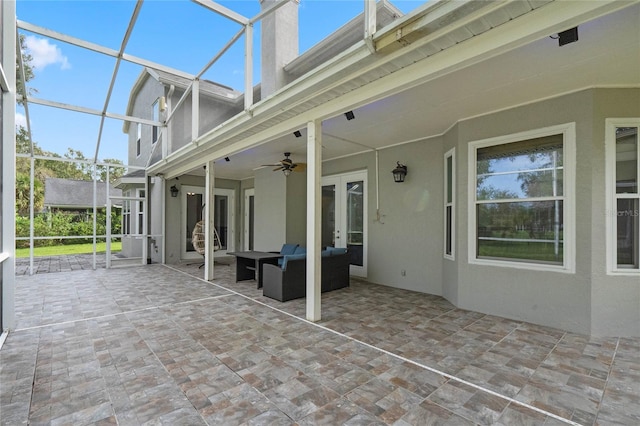 view of patio featuring an outdoor living space, glass enclosure, and ceiling fan