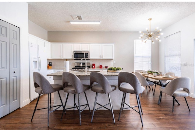 kitchen featuring white cabinets, light stone countertops, white fridge with ice dispenser, and dark hardwood / wood-style flooring