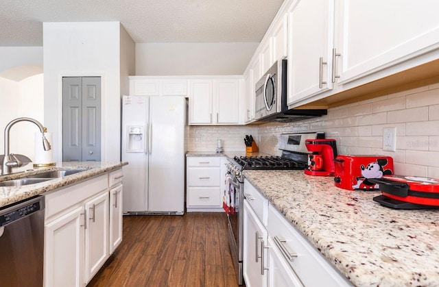 kitchen with stainless steel appliances, light stone countertops, dark hardwood / wood-style floors, a textured ceiling, and white cabinets