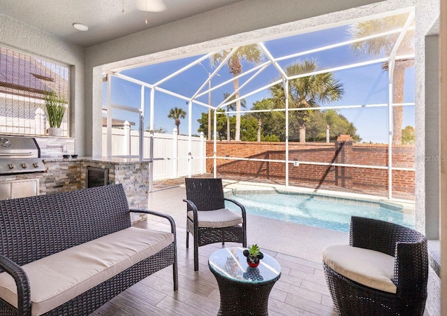 exterior space with grilling area, glass enclosure, a fenced in pool, and exterior kitchen