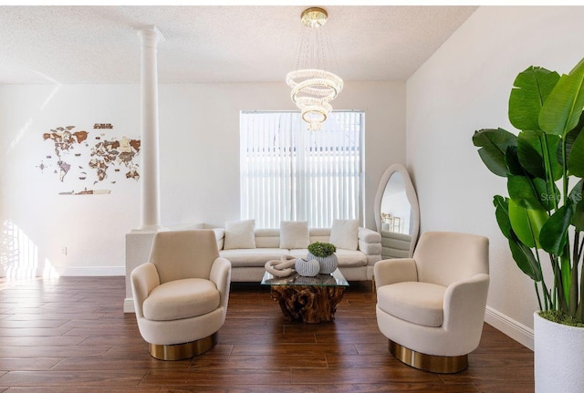 living room with dark wood-type flooring, a textured ceiling, ornate columns, and a notable chandelier