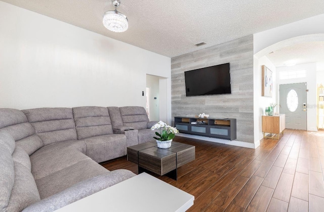 living room with a textured ceiling and dark hardwood / wood-style floors