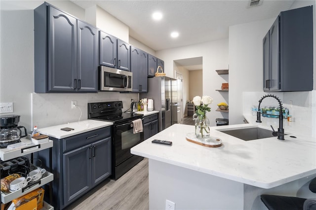 kitchen featuring kitchen peninsula, tasteful backsplash, stainless steel appliances, sink, and light hardwood / wood-style floors