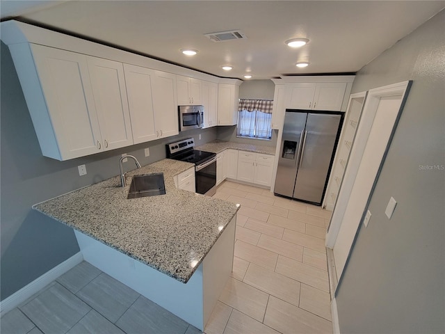 kitchen with kitchen peninsula, light stone counters, stainless steel appliances, sink, and white cabinets