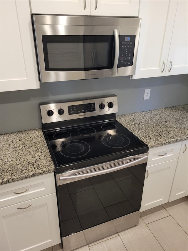 kitchen featuring white cabinets, light stone counters, light tile patterned floors, and stainless steel appliances