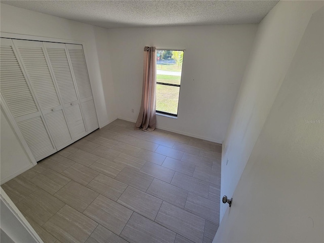 unfurnished bedroom featuring a textured ceiling and a closet