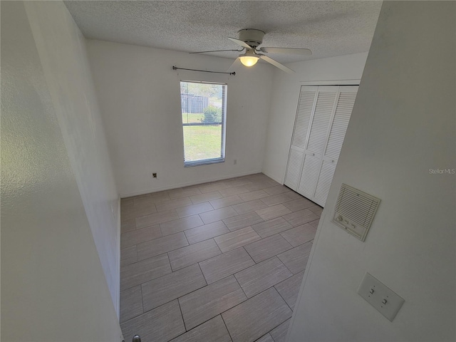 unfurnished bedroom with ceiling fan, a closet, and a textured ceiling