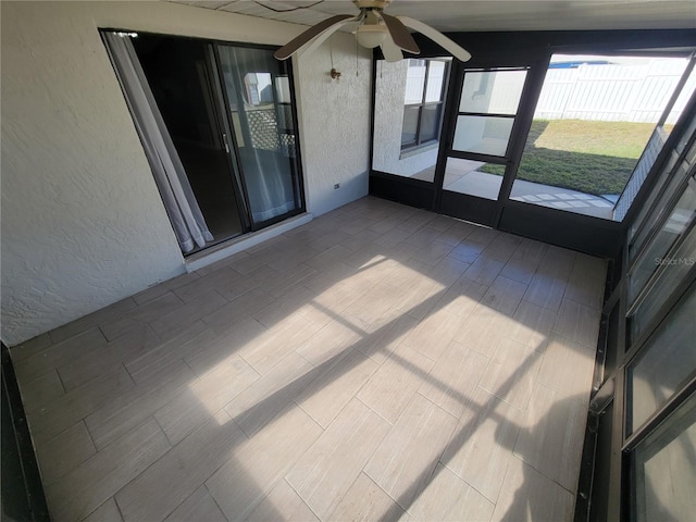 unfurnished sunroom with ceiling fan