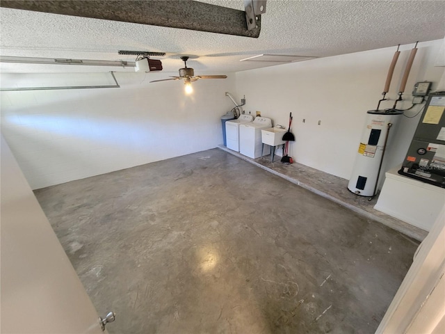 garage featuring a garage door opener, sink, ceiling fan, separate washer and dryer, and water heater