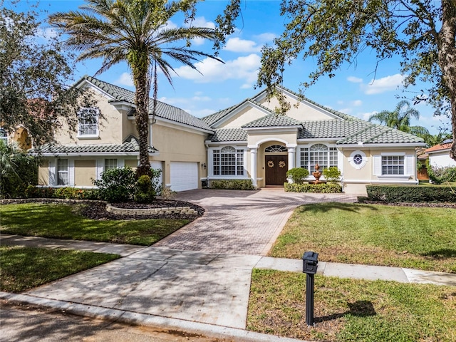 mediterranean / spanish home featuring a garage and a front yard