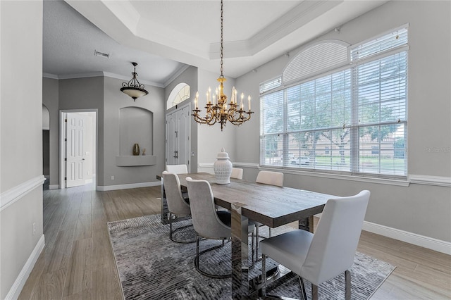 dining room with ornamental molding, hardwood / wood-style floors, and an inviting chandelier