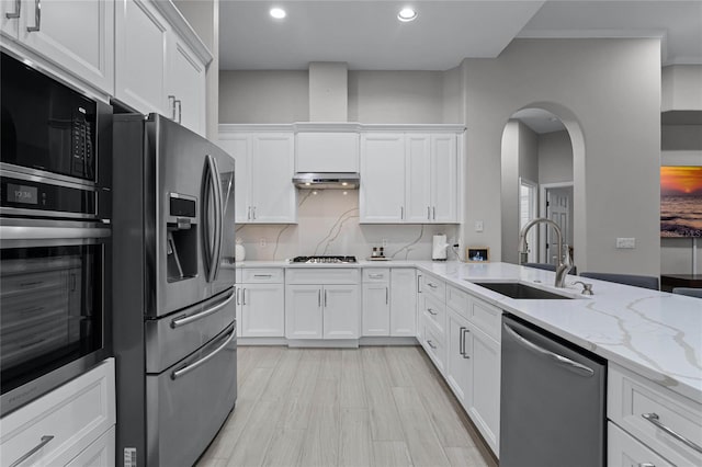 kitchen with white cabinetry, sink, light stone counters, appliances with stainless steel finishes, and tasteful backsplash