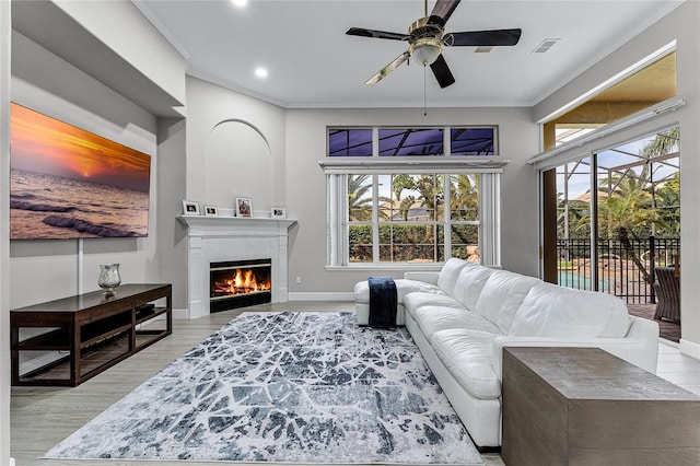 living room featuring light wood-type flooring, plenty of natural light, and crown molding