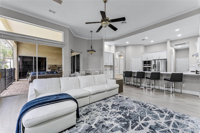 living room featuring light hardwood / wood-style floors, ceiling fan, and crown molding