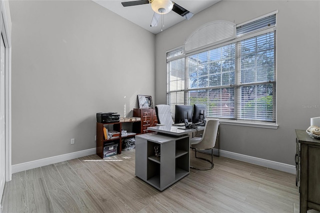 home office with light hardwood / wood-style floors and ceiling fan