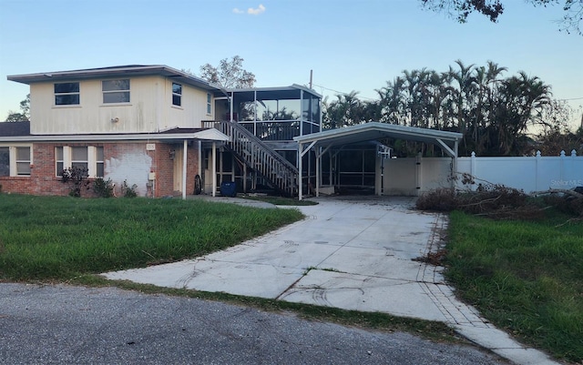 view of front facade featuring a sunroom, a carport, and a front lawn