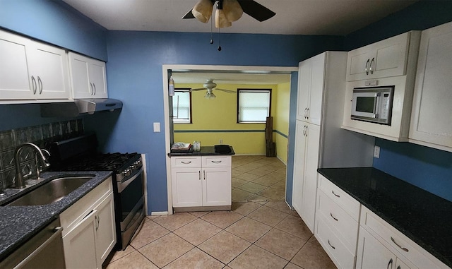 kitchen featuring stainless steel appliances, sink, dark stone counters, light tile patterned floors, and white cabinets