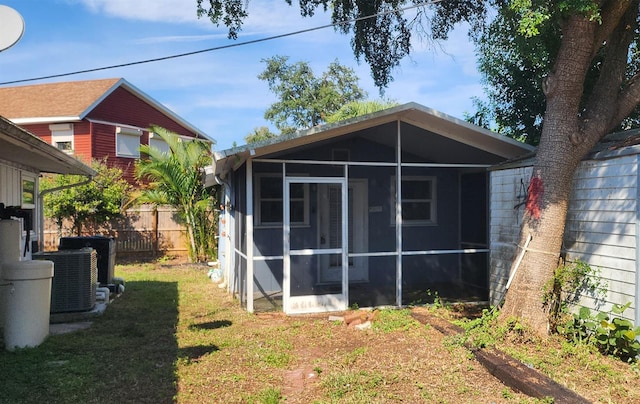 back of house featuring a sunroom and a lawn