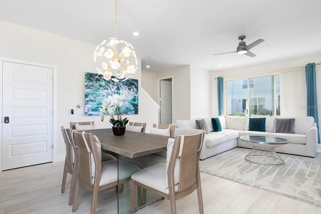 dining room with light wood-type flooring and ceiling fan with notable chandelier