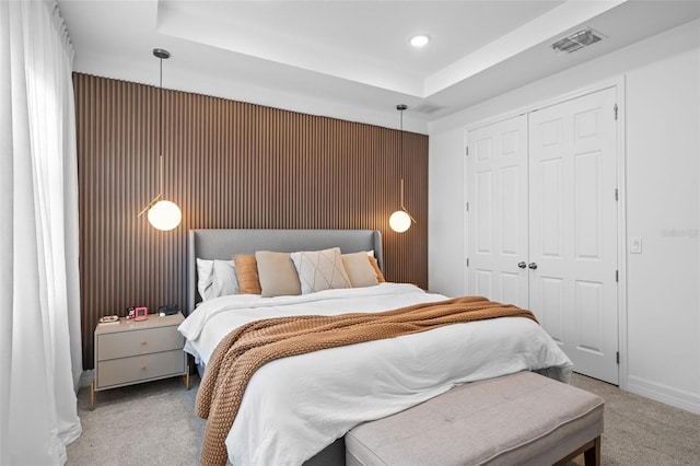 bedroom with carpet flooring, a tray ceiling, and a closet