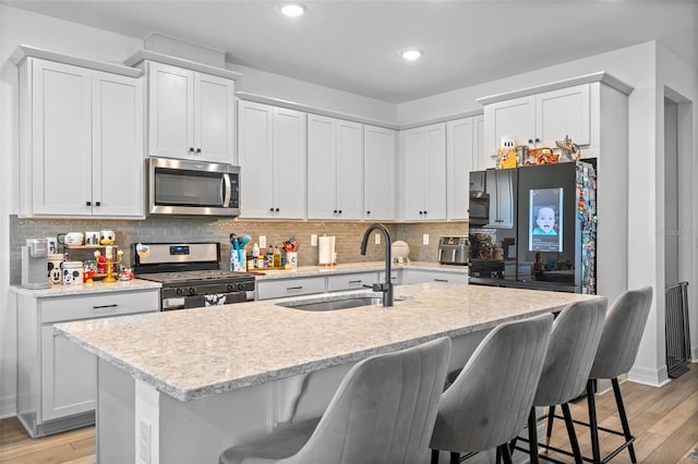 kitchen featuring white cabinetry, appliances with stainless steel finishes, and a center island with sink