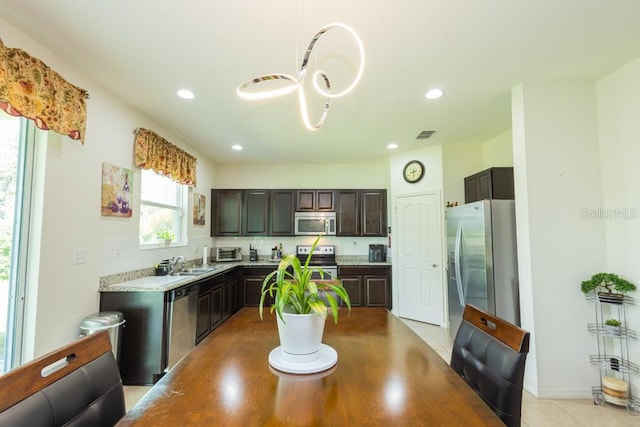 kitchen with stainless steel appliances, dark brown cabinets, sink, and light wood-type flooring