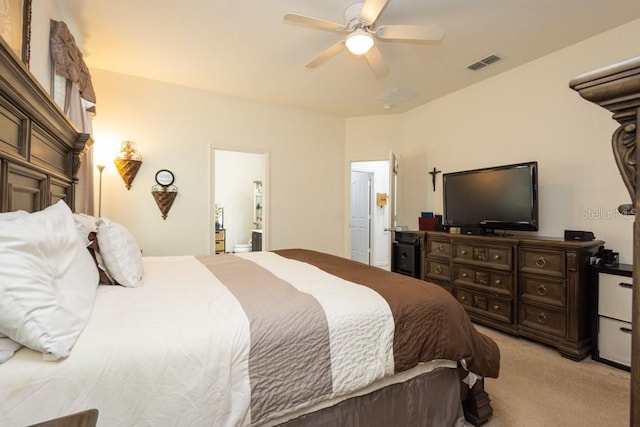 bedroom with ensuite bathroom, light carpet, and ceiling fan