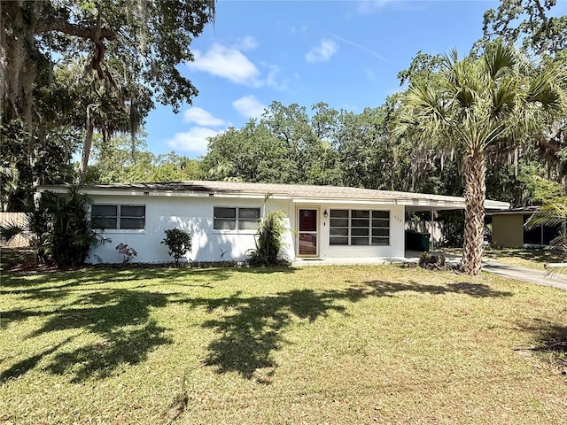 ranch-style home with stucco siding, a carport, concrete driveway, and a front yard