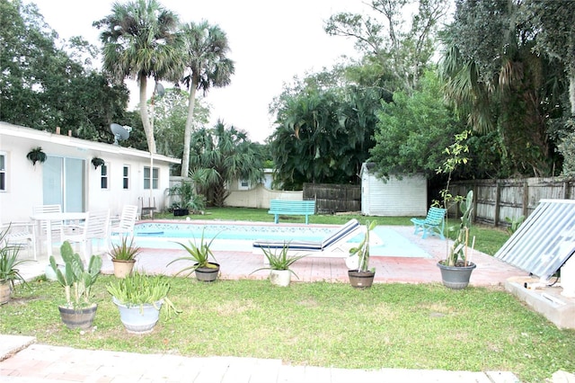 view of swimming pool featuring an outdoor structure, a patio, a fenced in pool, a yard, and a fenced backyard