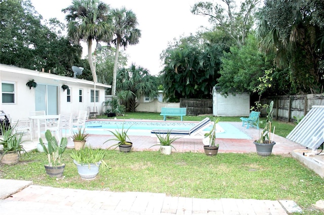 view of pool with an outbuilding, a lawn, a fenced backyard, and a patio area