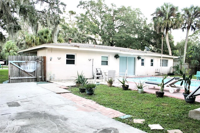 rear view of house with fence, a fenced in pool, a gate, a patio area, and stucco siding