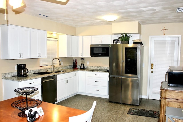 kitchen with white cabinets, black appliances, light stone countertops, and a sink