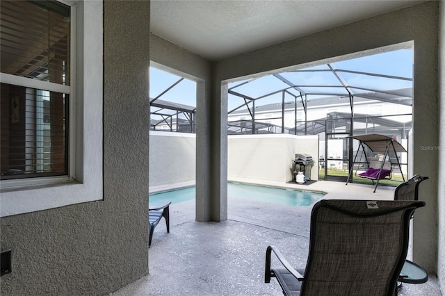 view of pool with glass enclosure and a patio