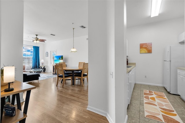 kitchen featuring white cabinetry, ceiling fan, white refrigerator, pendant lighting, and light hardwood / wood-style floors