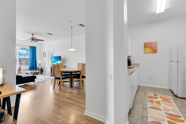 kitchen with pendant lighting, white appliances, white cabinets, light hardwood / wood-style flooring, and ceiling fan