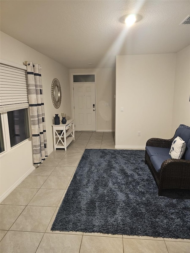 living area featuring a textured ceiling and light tile patterned floors