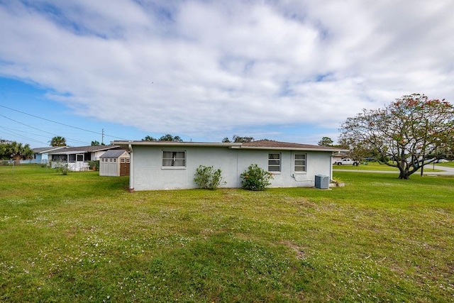 rear view of property with cooling unit and a yard