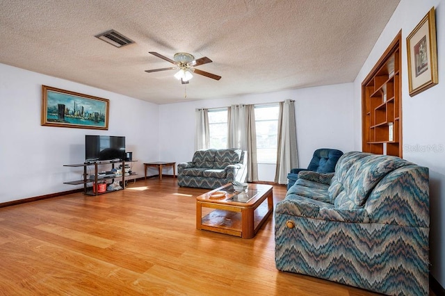 living room with light hardwood / wood-style flooring, a textured ceiling, and ceiling fan