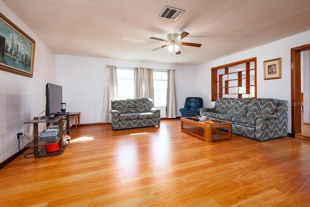 living room featuring a textured ceiling, ceiling fan, and light hardwood / wood-style flooring