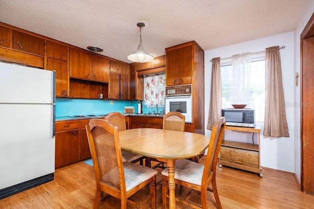 dining room with sink, a textured ceiling, and light hardwood / wood-style flooring