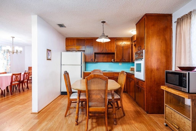 dining space featuring a textured ceiling, light hardwood / wood-style flooring, and a chandelier