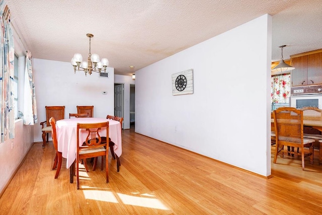 dining room featuring light hardwood / wood-style floors, a chandelier, and a textured ceiling