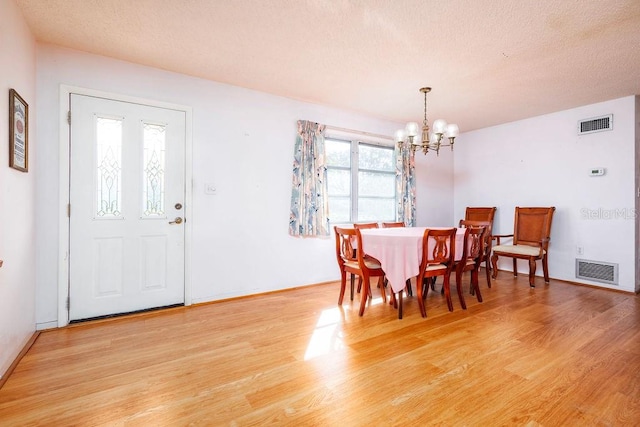 dining room featuring a textured ceiling, light hardwood / wood-style flooring, and a notable chandelier