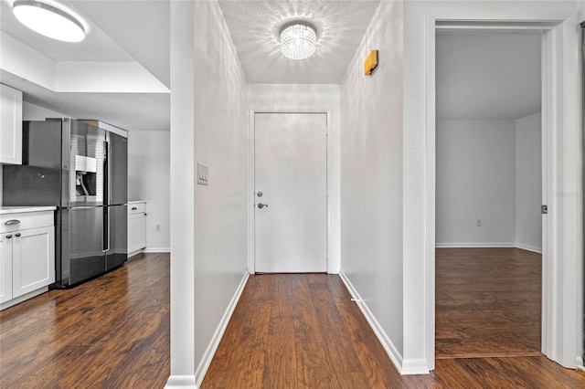 corridor with dark wood-type flooring and a chandelier