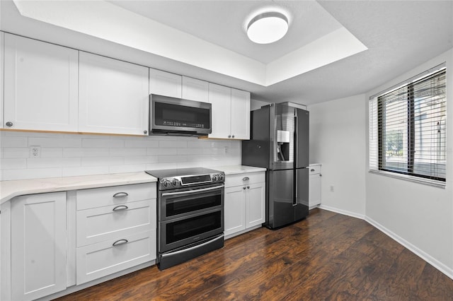 kitchen featuring white cabinetry, appliances with stainless steel finishes, dark hardwood / wood-style floors, a textured ceiling, and backsplash