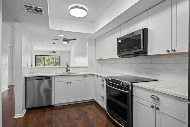 kitchen with white cabinetry, sink, appliances with stainless steel finishes, dark wood-type flooring, and vaulted ceiling