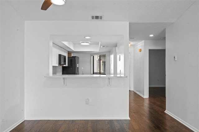 interior space featuring dark hardwood / wood-style flooring, ceiling fan, and a tray ceiling